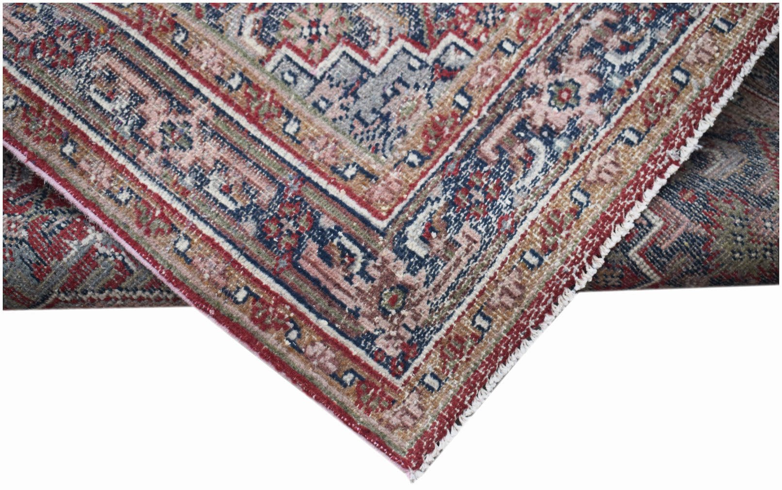 A handwoven vintage Persian rug featuring intricate geometric patterns in faded red and blue tones.