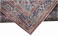 A handwoven vintage Persian rug featuring intricate geometric patterns in faded red and blue tones.