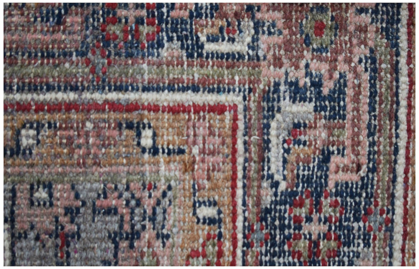 A close-up view of a vintage Persian rug featuring intricate geometric patterns in wool.