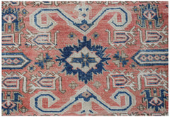 Vintage Persian rug with coral, blue, and cream geometric patterns.