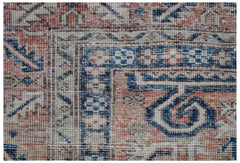 A close-up of a vintage handwoven Persian rug featuring geometric patterns in blue and terracotta.