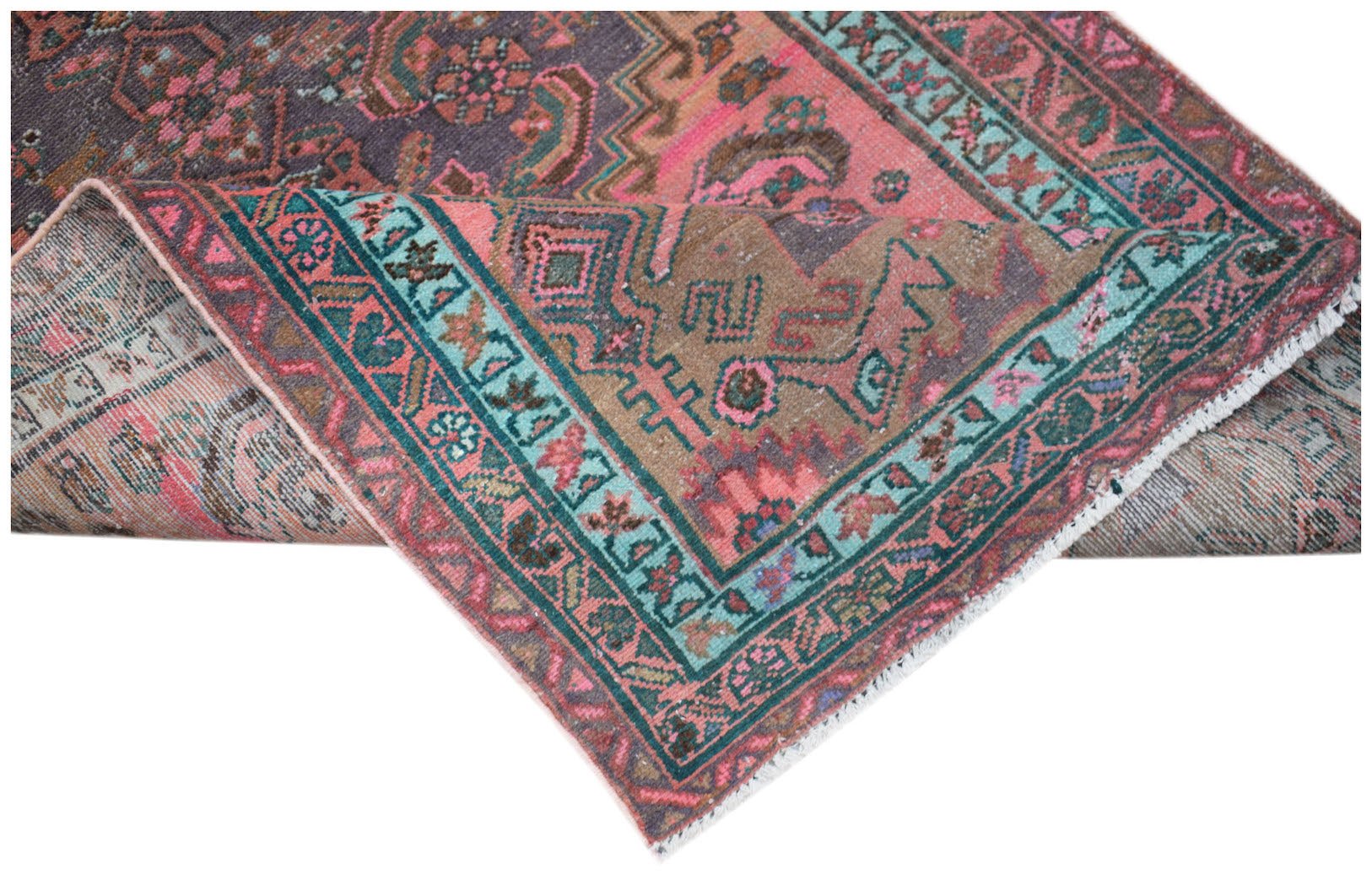 A vintage handwoven Persian rug featuring a distressed floral pattern in pink, teal, and brown.