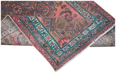 A vintage handwoven Persian rug featuring a distressed floral pattern in pink, teal, and brown.
