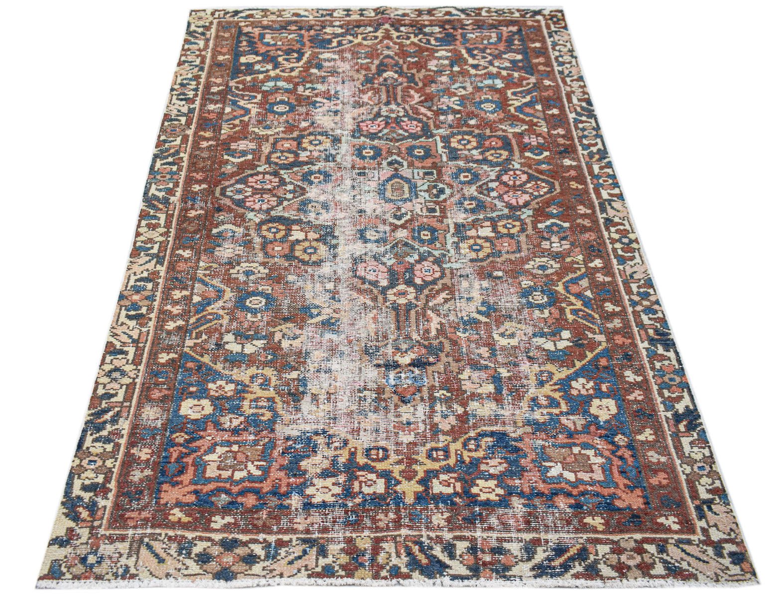 A rectangular vintage Persian rug featuring a distressed floral pattern in red, blue, and cream.