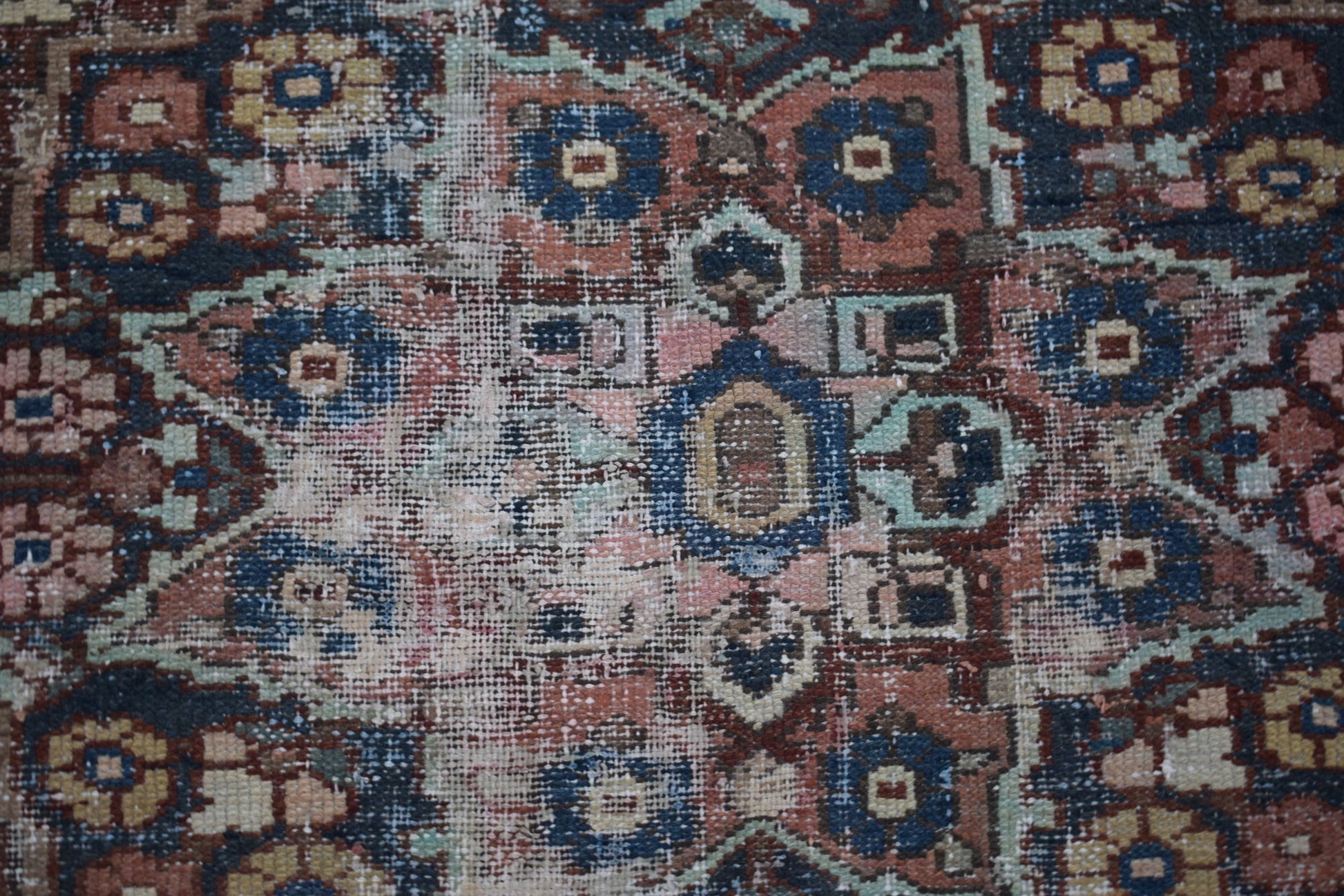 A handwoven vintage Persian rug featuring a geometric floral pattern in faded blue and red tones.
