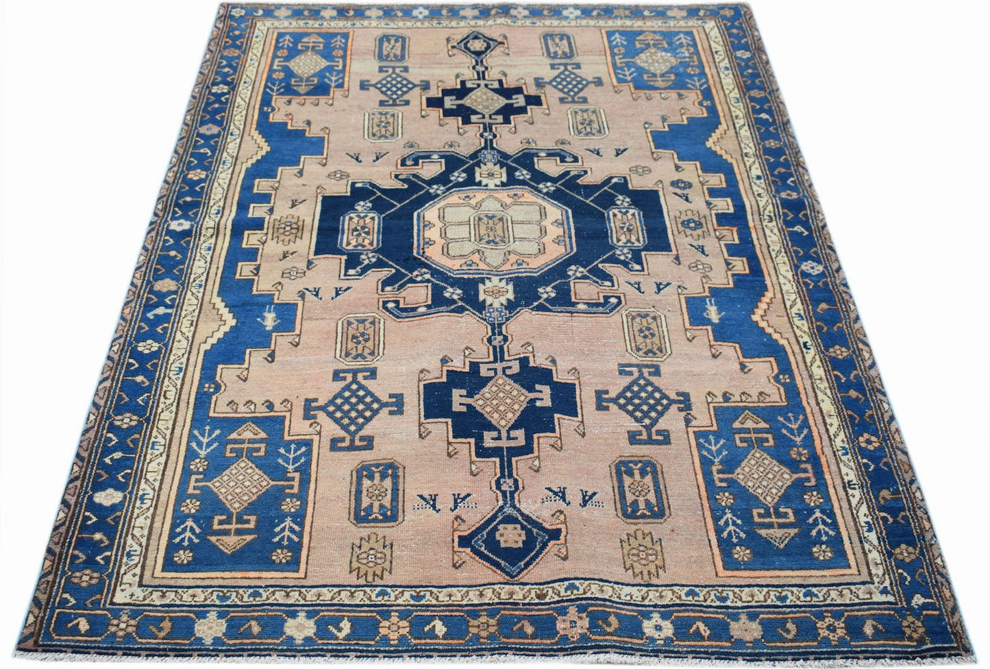 A handwoven vintage Persian rug featuring a geometric blue and beige pattern on a wool pile.