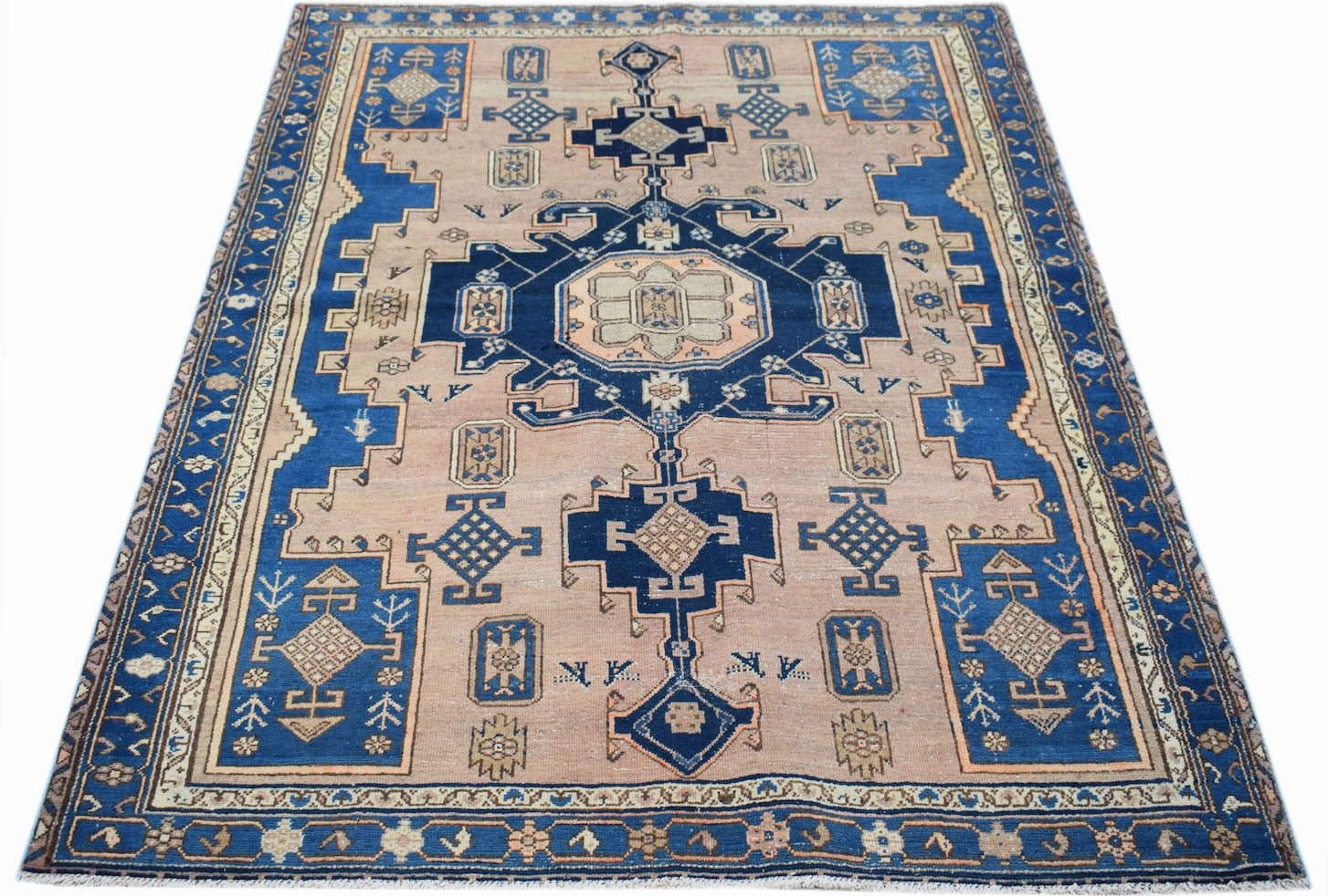 A handwoven vintage Persian rug featuring a geometric blue and beige pattern on a wool pile.