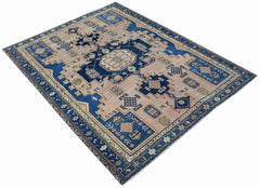 A handwoven vintage Persian rug featuring a blue geometric medallion on a light brown field.