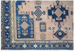 A handwoven vintage Persian rug featuring geometric blue and tan patterns on a wool pile.
