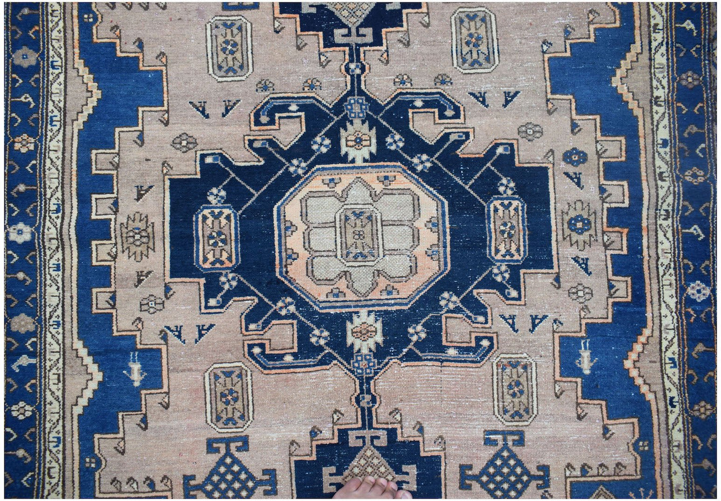 A handwoven vintage Persian wool rug featuring a geometric blue and beige medallion pattern.