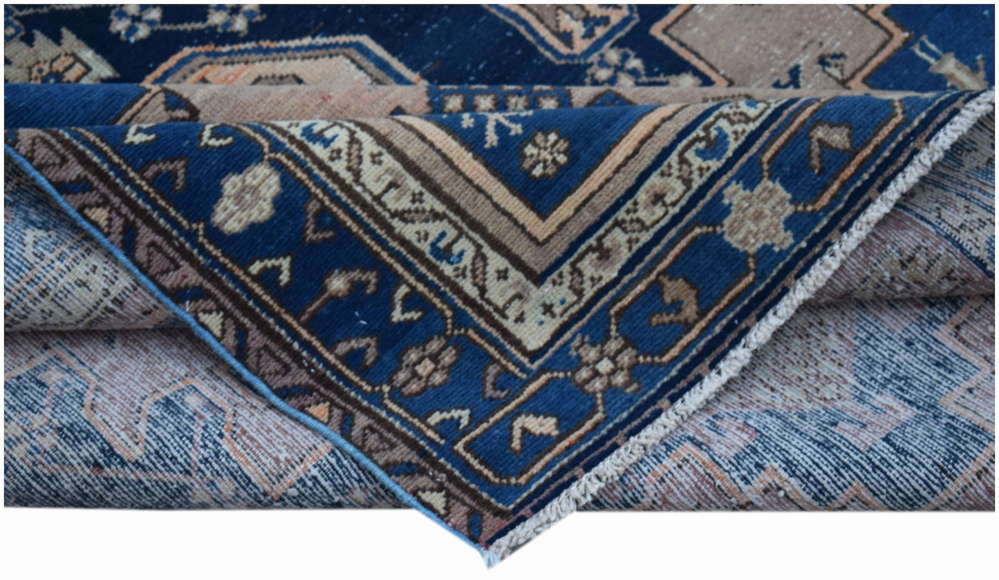 A vintage handwoven Persian rug featuring a blue field with intricate geometric patterns.