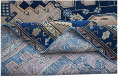 A handwoven vintage Persian rug featuring a geometric pattern in blue and beige tones.