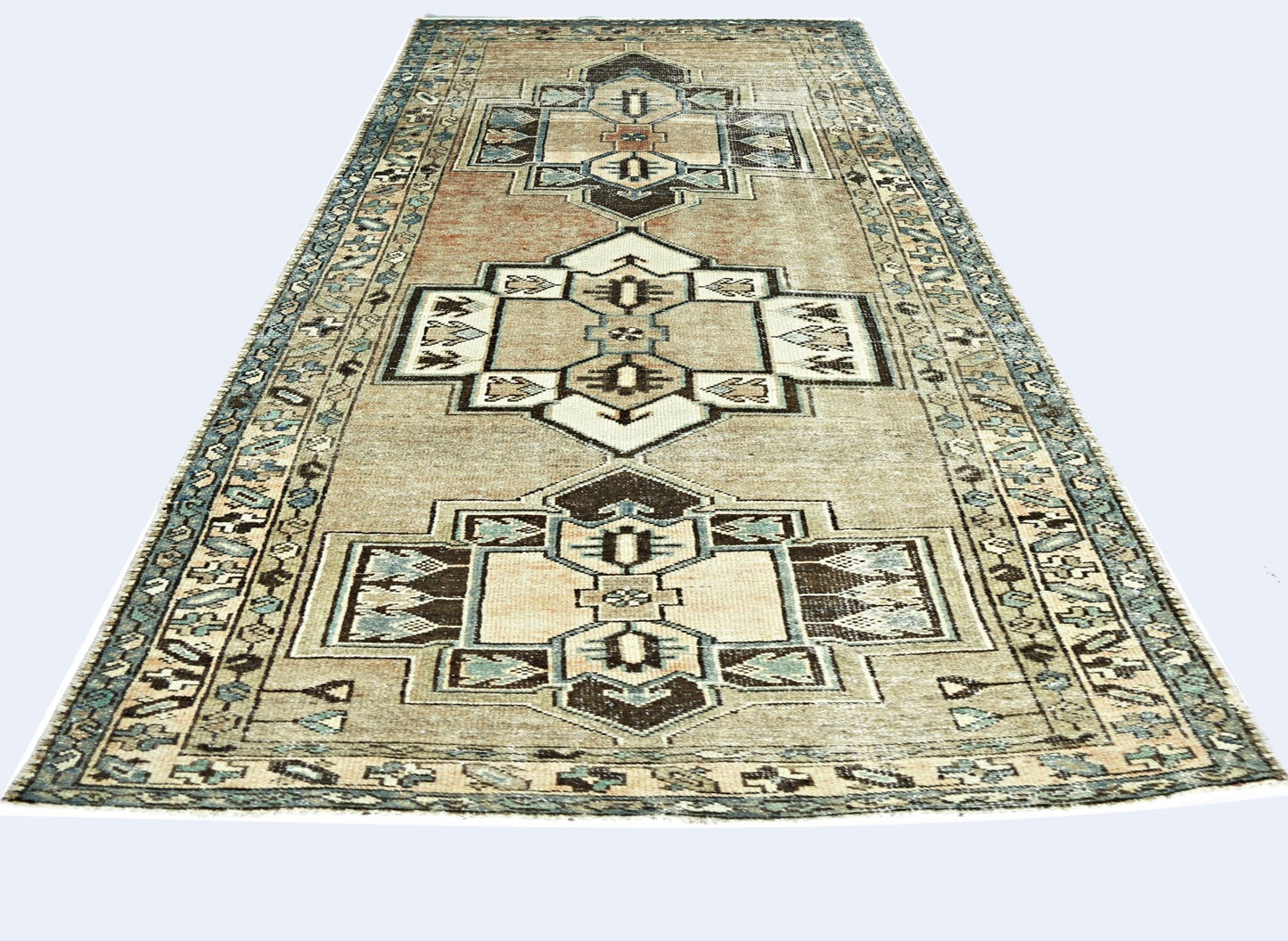 A vintage handmade Persian rug featuring geometric medallions in muted earth tones and blue.