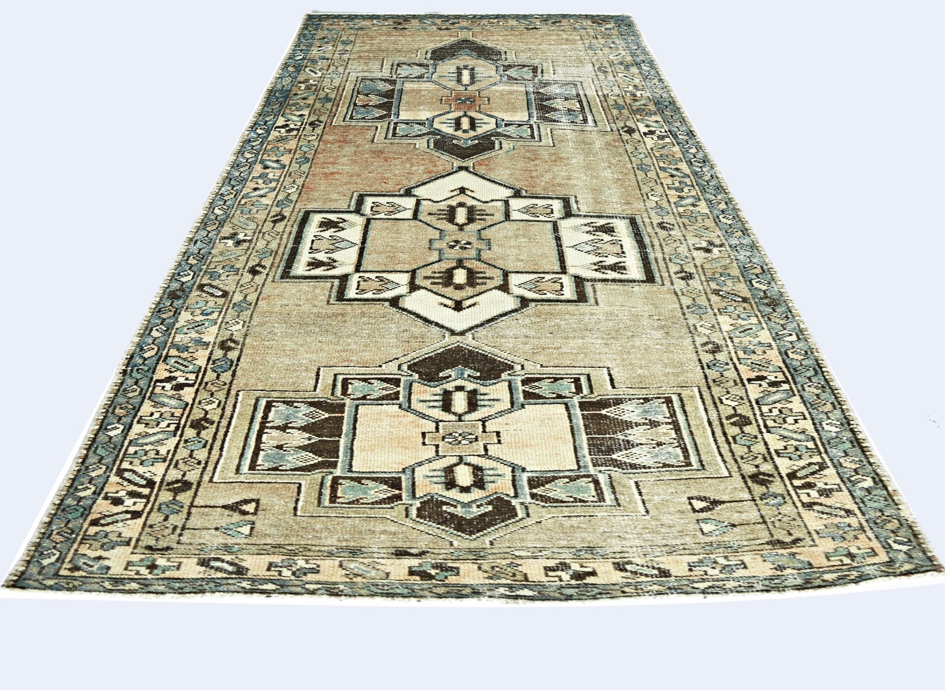 A vintage handmade Persian rug featuring geometric medallions in muted earth tones and blue.