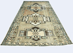 A vintage handmade Persian rug featuring geometric medallions in muted earth tones and blue.