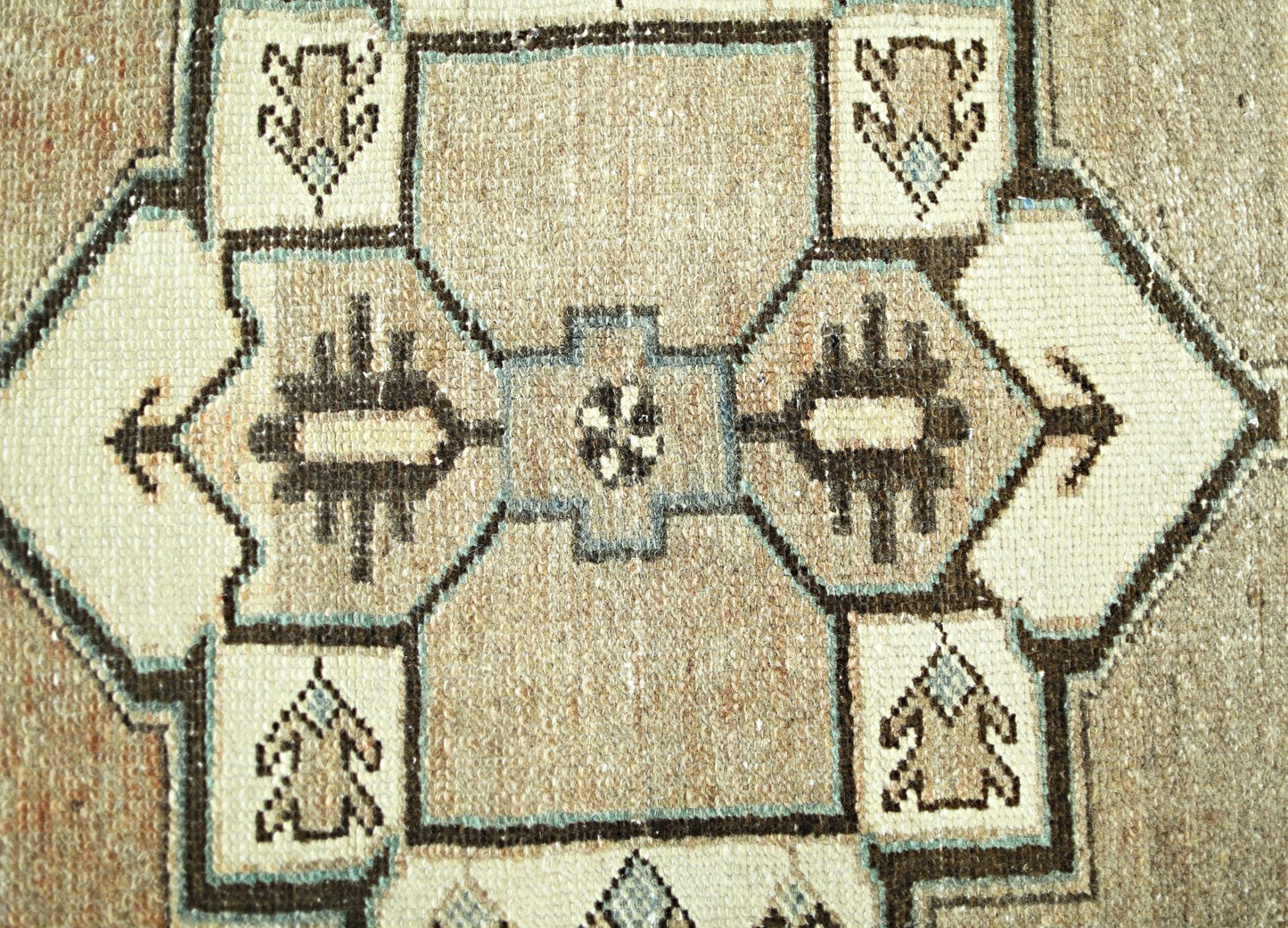A vintage Persian rug featuring a geometric pattern in shades of beige, brown, and blue.