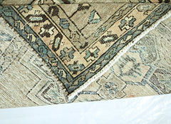 A folded vintage Persian rug featuring intricate geometric patterns in muted earth tones.