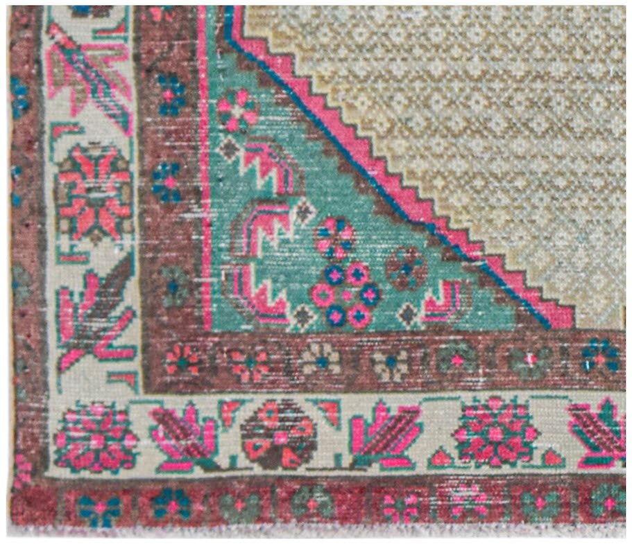 Vintage Persian rug with intricate floral patterns in pink, teal, and brown.