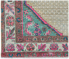 Vintage Persian rug with intricate floral patterns in pink, teal, and brown.