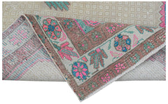A vintage handwoven Persian rug featuring a floral pattern in pink, blue, and green on beige.