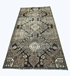 A handmade vintage Persian rug featuring a geometric pattern in shades of brown, blue, and cream.