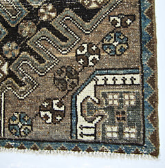 A corner view of a vintage handmade Persian rug featuring intricate geometric patterns in wool.