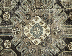 A vintage Persian rug featuring a geometric diamond pattern in shades of brown, cream, and blue.