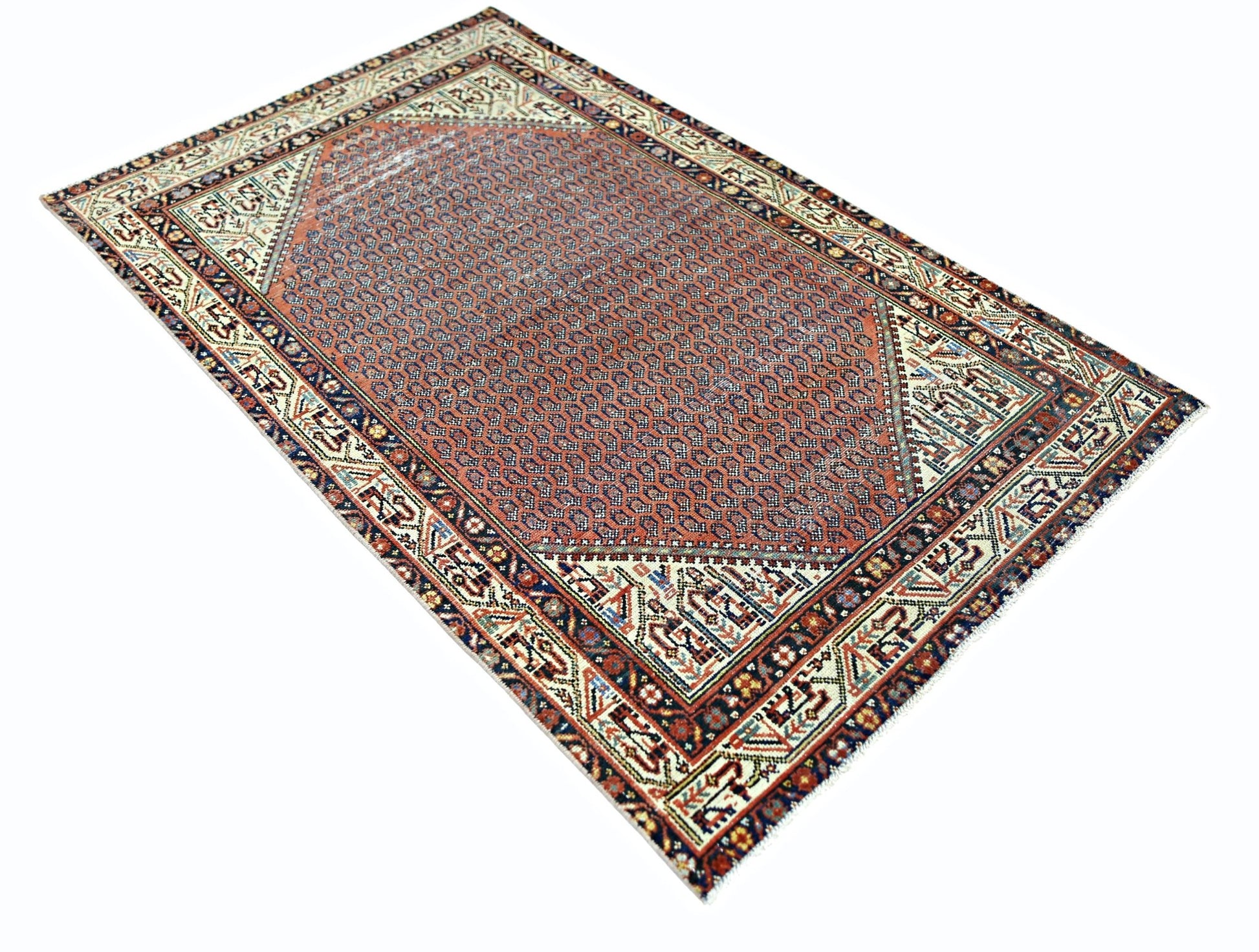 A vintage Persian rug featuring a geometric pattern in red, blue, and cream on a wool pile.
