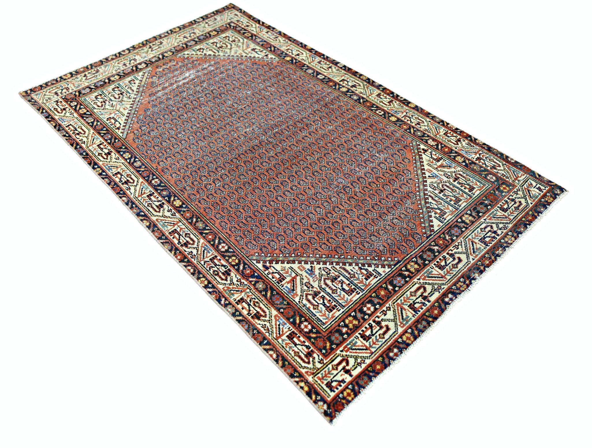 A vintage Persian rug featuring a geometric pattern in red, blue, and cream on a wool pile.