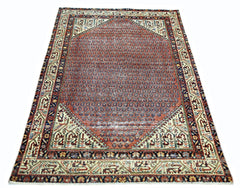 A vintage Persian rug featuring a central hexagonal medallion with a repeating geometric pattern.