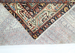 A corner of a vintage Persian rug is folded back to reveal its intricate wool pile and cotton base.
