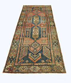 A handmade vintage Persian runner rug featuring geometric patterns in blue, red, and green tones.
