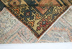 A corner of a vintage handmade Persian rug is folded back to reveal its wool pile and cotton base.