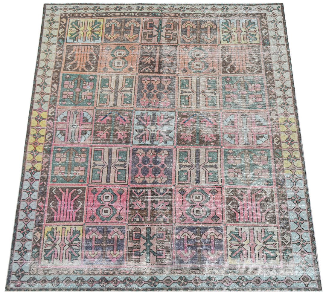Vintage Persian rug with a patchwork of geometric patterns in muted colors.