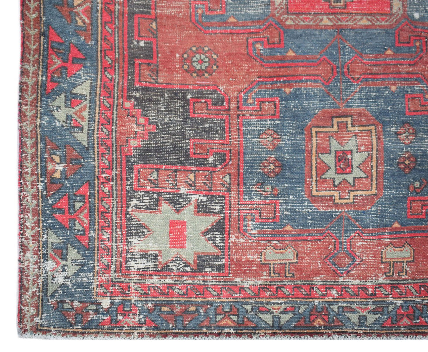 A vintage handwoven Persian rug featuring geometric patterns in shades of red, blue, and grey.