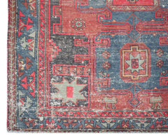 A vintage handwoven Persian rug featuring geometric patterns in shades of red, blue, and grey.