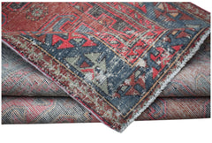 A vintage handwoven Persian rug featuring a distressed red and blue geometric pattern.