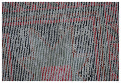 A close-up of a handwoven vintage Persian rug featuring a faded geometric pattern in red and grey.