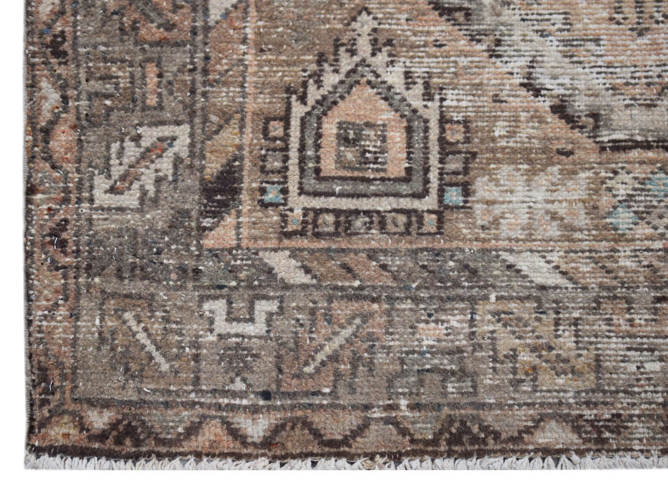 A handwoven vintage Persian rug featuring a distressed geometric pattern in muted earth tones.