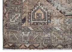 A handwoven vintage Persian rug featuring a distressed geometric pattern in muted earth tones.