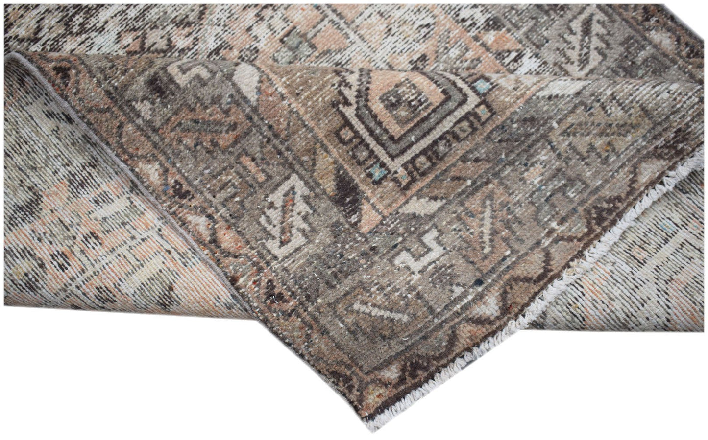 A handwoven vintage Persian rug featuring a faded geometric pattern in shades of brown and peach.