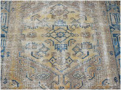 A handwoven vintage Persian rug featuring a geometric medallion pattern in blue and tan tones.