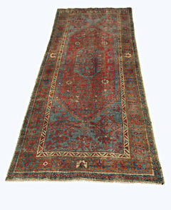 A vintage handmade Persian rug featuring a traditional geometric pattern in red and blue tones.