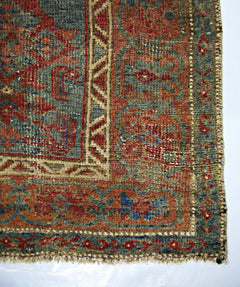 A close-up of a vintage handmade Persian rug featuring intricate geometric patterns in red and blue.