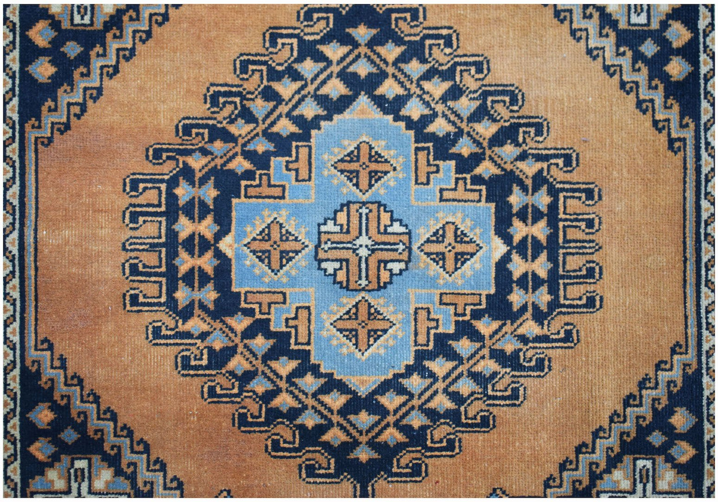 A vintage handwoven Persian rug featuring a geometric blue and orange medallion pattern.