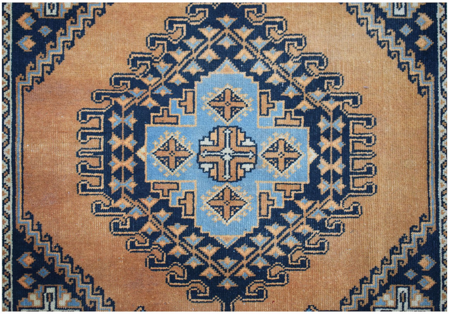 A vintage handwoven Persian rug featuring a geometric blue and orange medallion pattern.