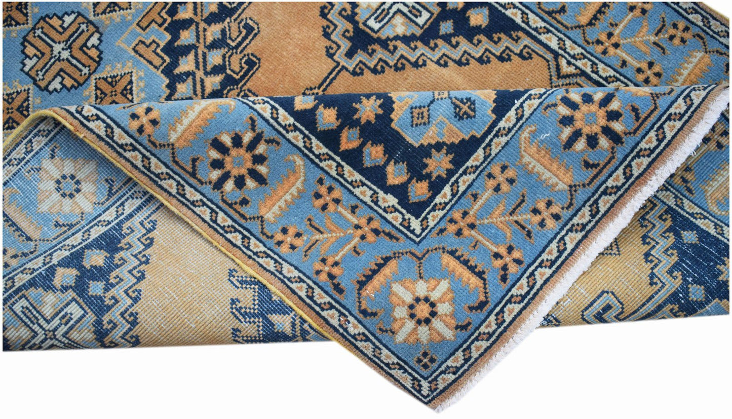 A vintage handwoven Persian rug featuring geometric patterns in shades of blue and orange.
