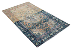 A vintage handwoven Persian rug featuring a faded geometric pattern in blue, orange, and beige.
