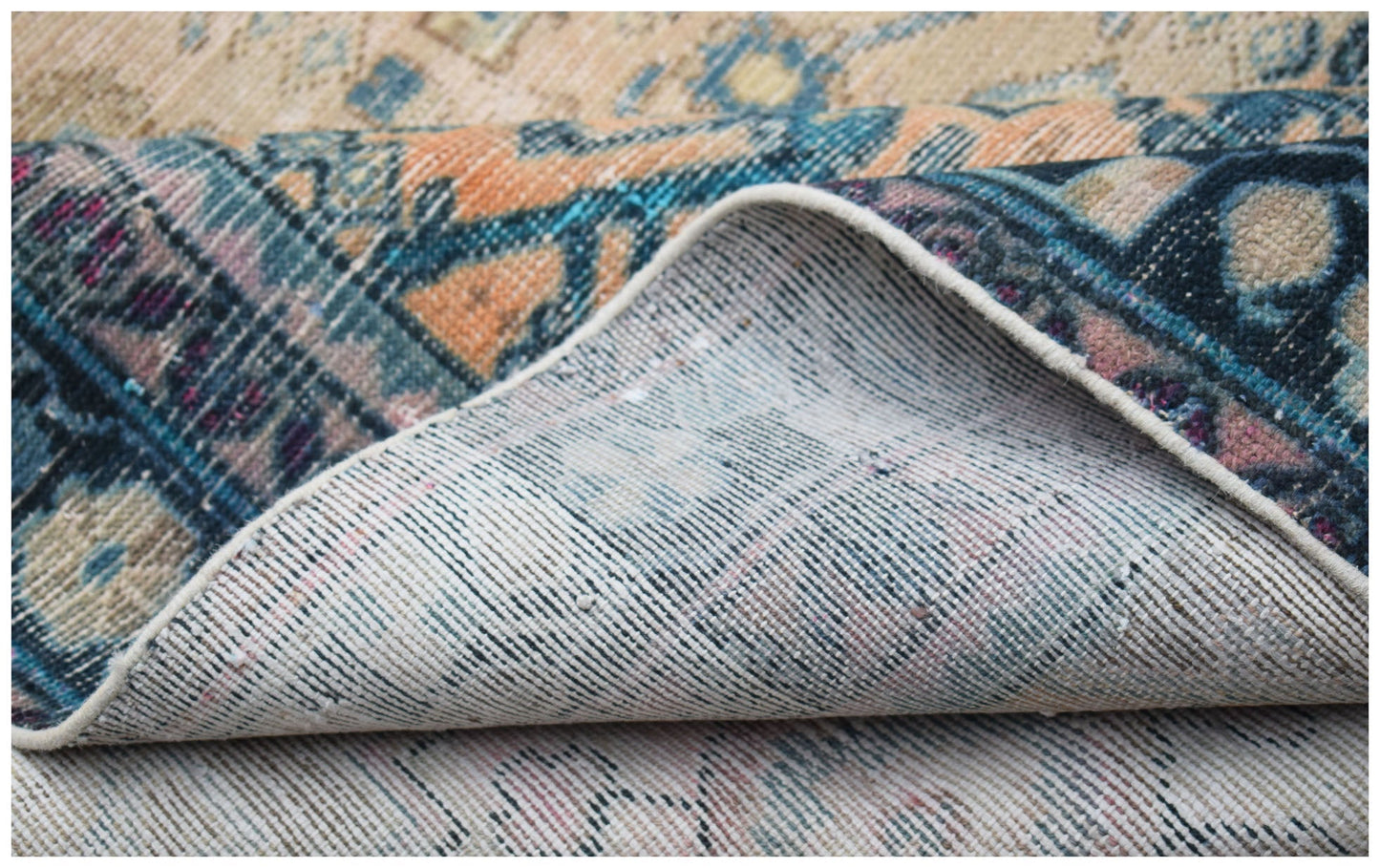 A folded vintage Persian rug featuring intricate patterns in blue, orange, and cream tones.