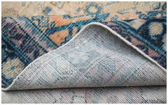 A folded vintage Persian rug featuring intricate patterns in blue, orange, and cream tones.